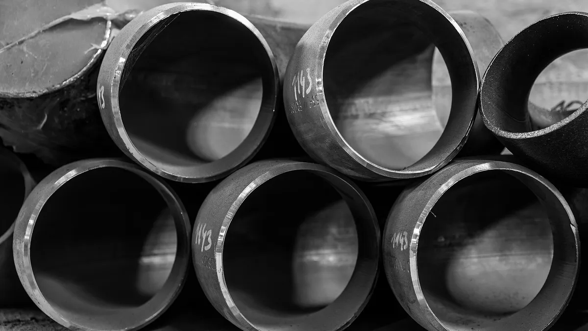 Stacks of large-bore steel pipes at an industrial supply yard