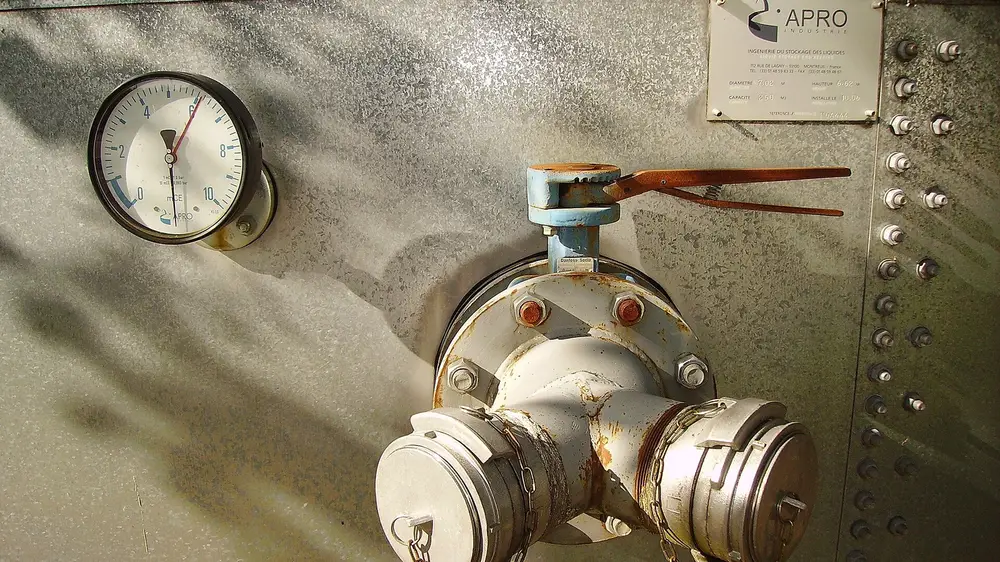 Pressure gauge and valve assembly mounted on a riveted steel vessel