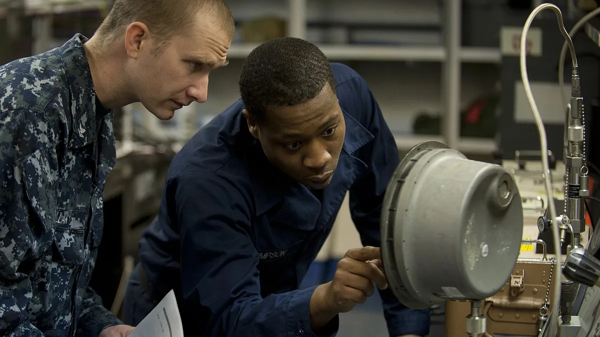 Two technicians inspecting a cylindrical instrument in a lab