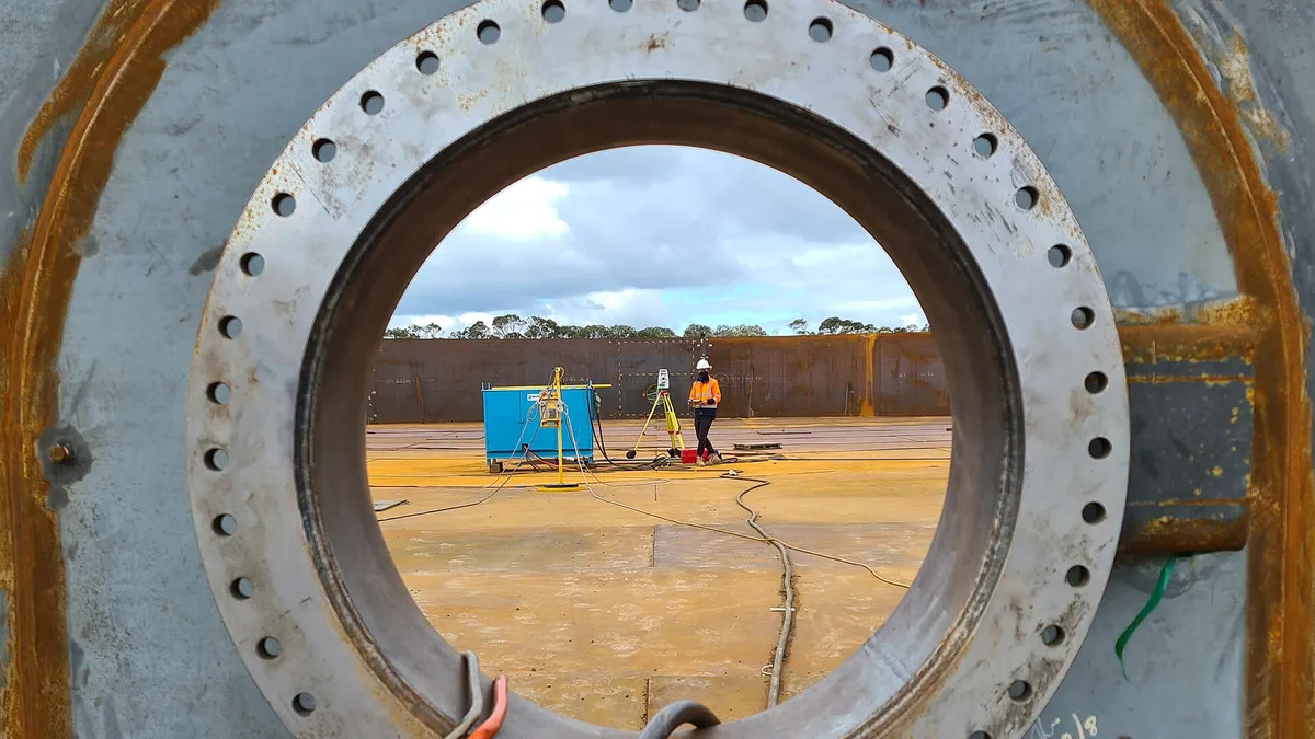 Circular bolted flange fixture with red tubing on a test rig