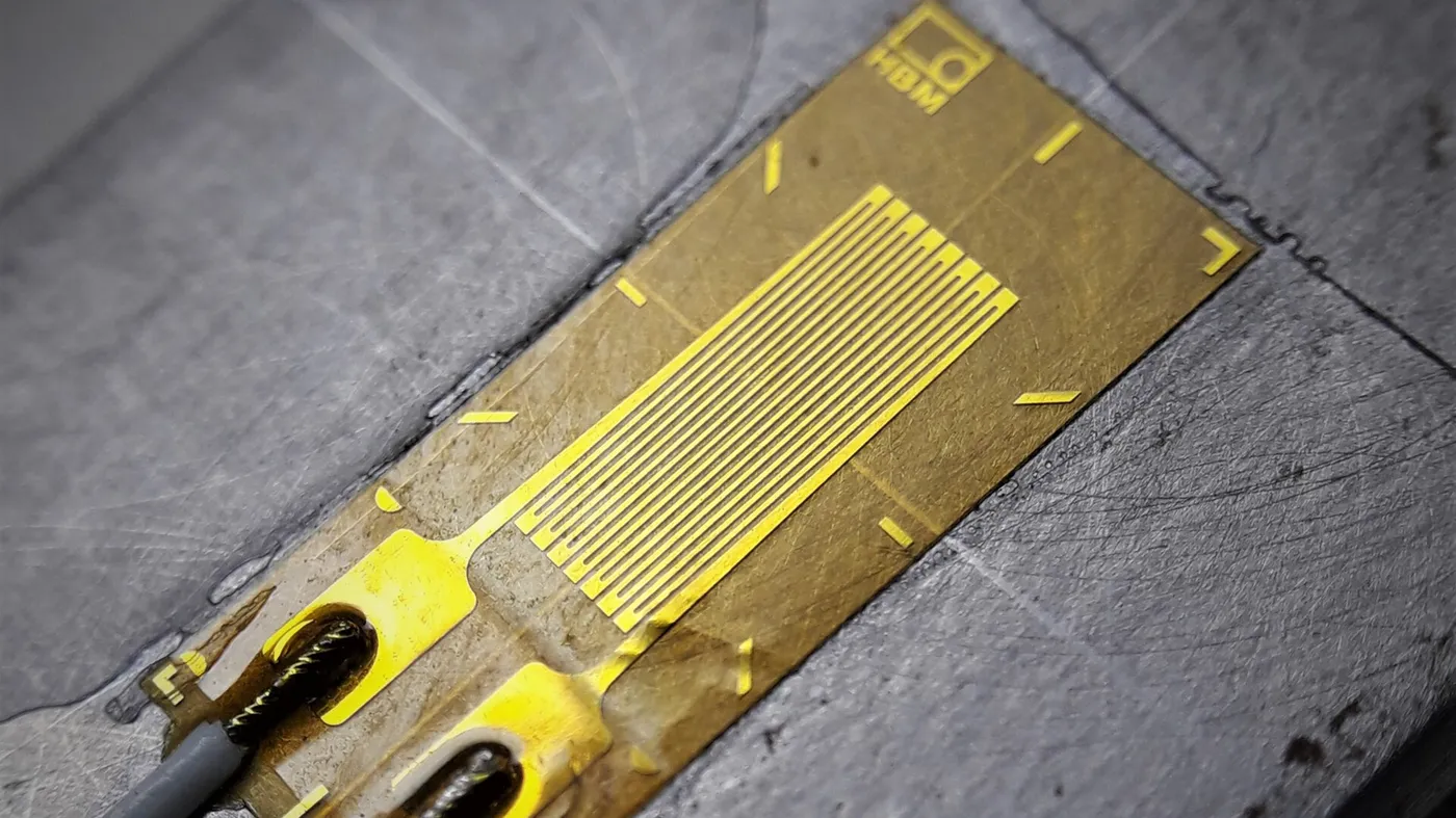 Bonded foil strain gauge with lead wires on a machined metal surface